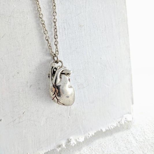 Handmade in New Zealand, this is a silver necklace with an anatomical heart pendant and red enamel detailing.