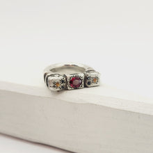 Load image into Gallery viewer, The Ruins Ring by Vaune Mason echoes anciant architectural colomns cast in chunky sterling silver. This ring is set with an oval red spinel at the centre, and on either side are small golden sapphires with two tiny black spinels.