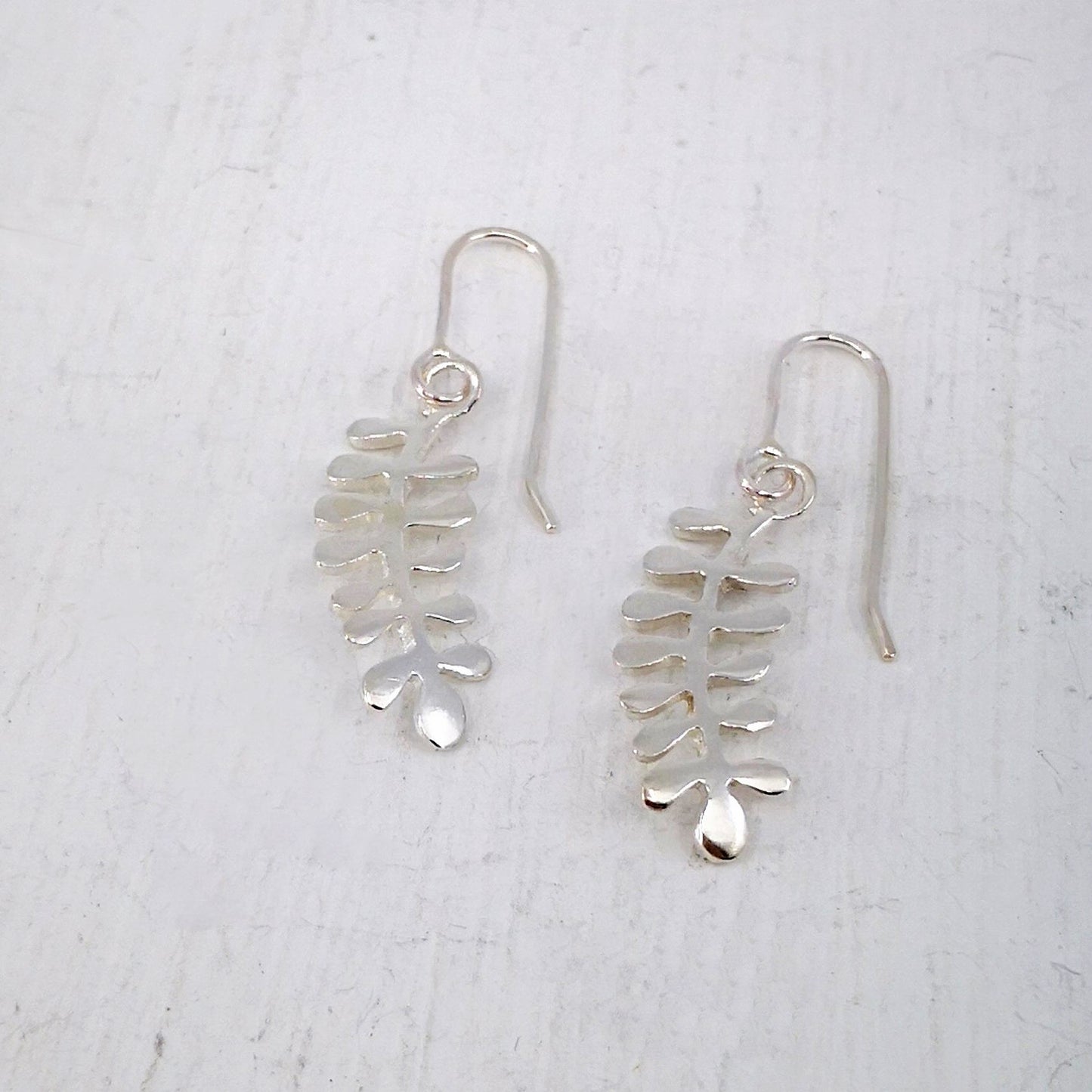 These light silver earrings are hand crafted in the shape of the NZ native Kowhai leaf. Made by Ruru Jewellery and available at Mason and Collins.