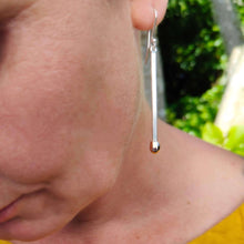 Load image into Gallery viewer, Our mid-40's female model stands in front of sunny trees in a gold linen dress and wears the Live Matchstick earrings handcrafted in solid sterling silver with cleverly made 9ct rose gold heads by David Mcleod.