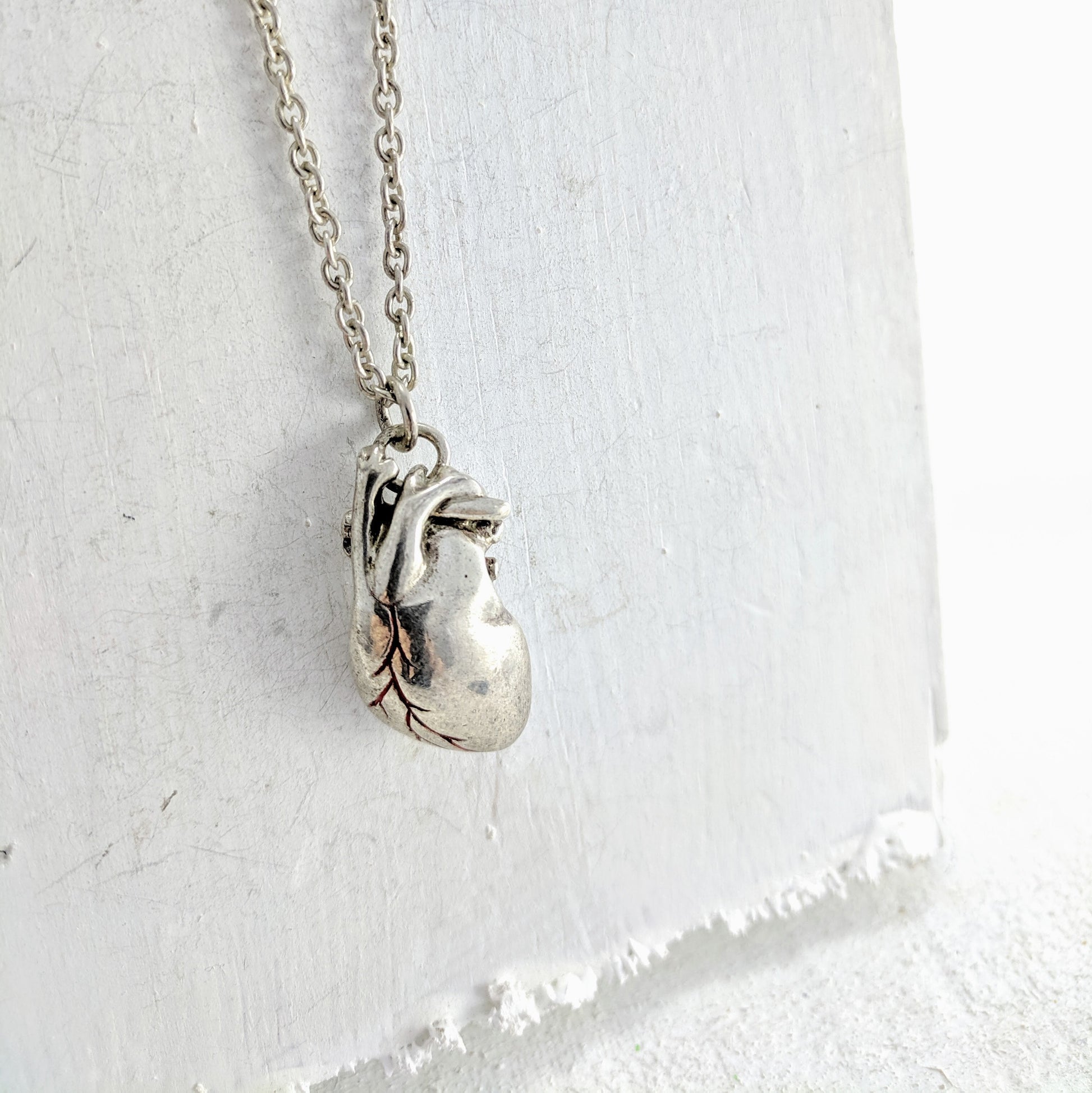 Handmade in New Zealand, this is a silver necklace with an anatomical heart pendant and red enamel detailing.