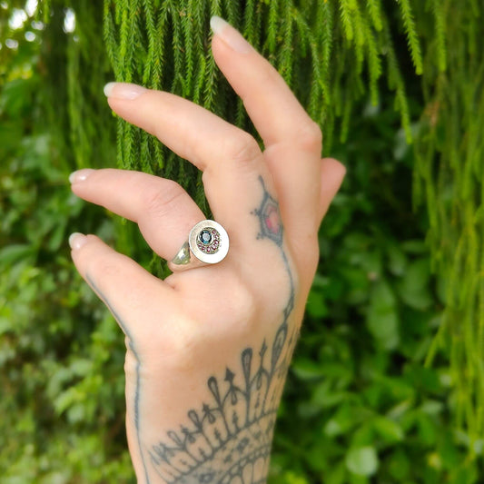 A heavy solid silver ring set with sapphire and rubies in the shape of an eclipse. Hand made quality silver jewellery by NZ jewellers at Mason and Collins. 