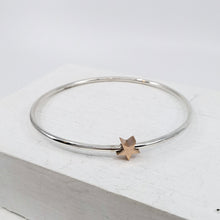 Load image into Gallery viewer, This sleek bracelet is hand-crafted in round sterling silver bar with a solid rose gold star charm. Available now at Mason and Collins.
