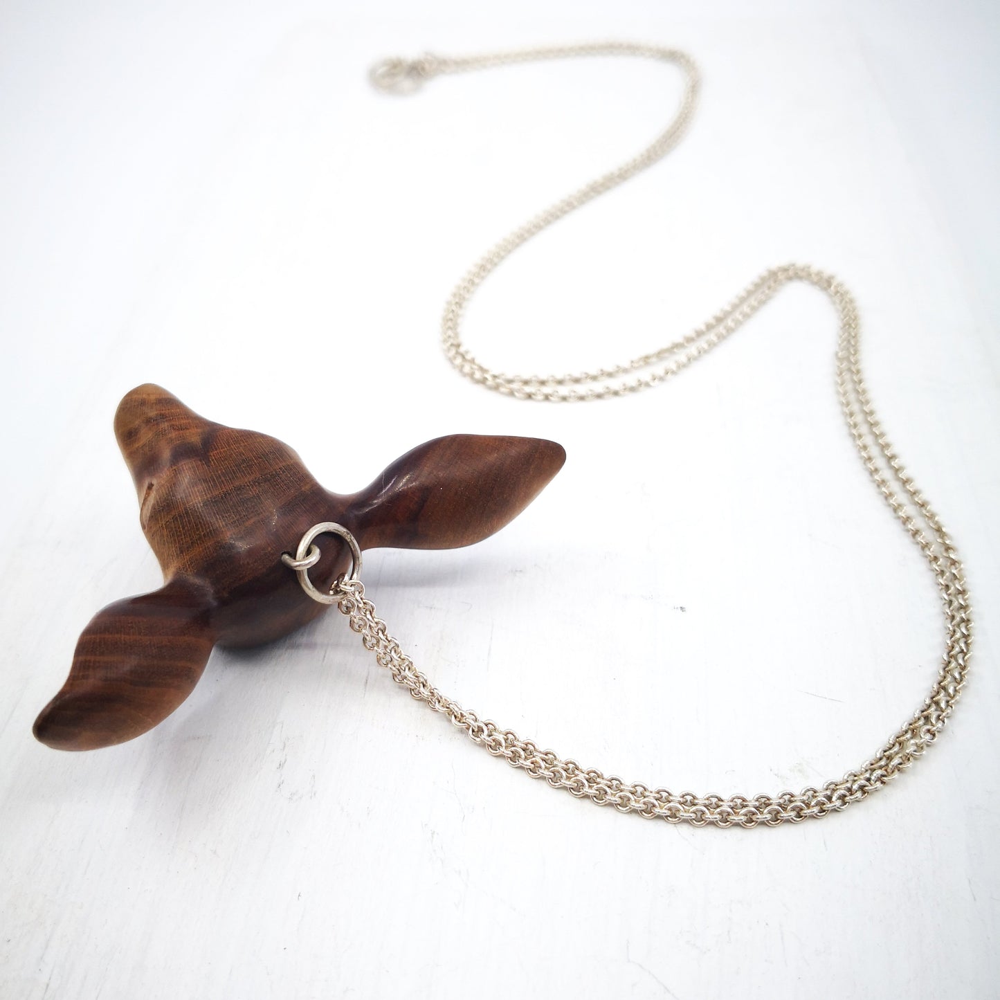 The Doe's Head Necklace is hand carved in richly coloured cherry wood, finished with oils and beeswax and hung on a long solid sterling silver chain. Crafted by NZ jeweller Vaune Mason.