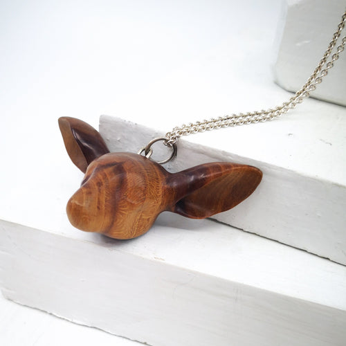 The Doe's Head Necklace is hand carved in richly coloured cherry wood, finished with oils and beeswax and hung on a long solid sterling silver chain. Crafted by NZ jeweller Vaune Mason.