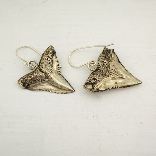 The front and back of the white bronze shark teeth earrings. By Keri-Mei Zagrobelna