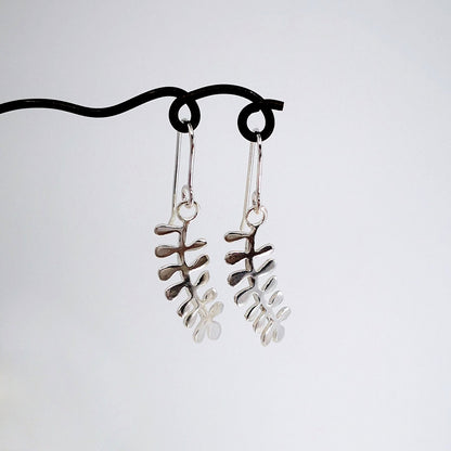 These light silver earrings are hand crafted in the shape of the NZ native Kowhai leaf. Made by Ruru Jewellery and available at Mason and Collins.