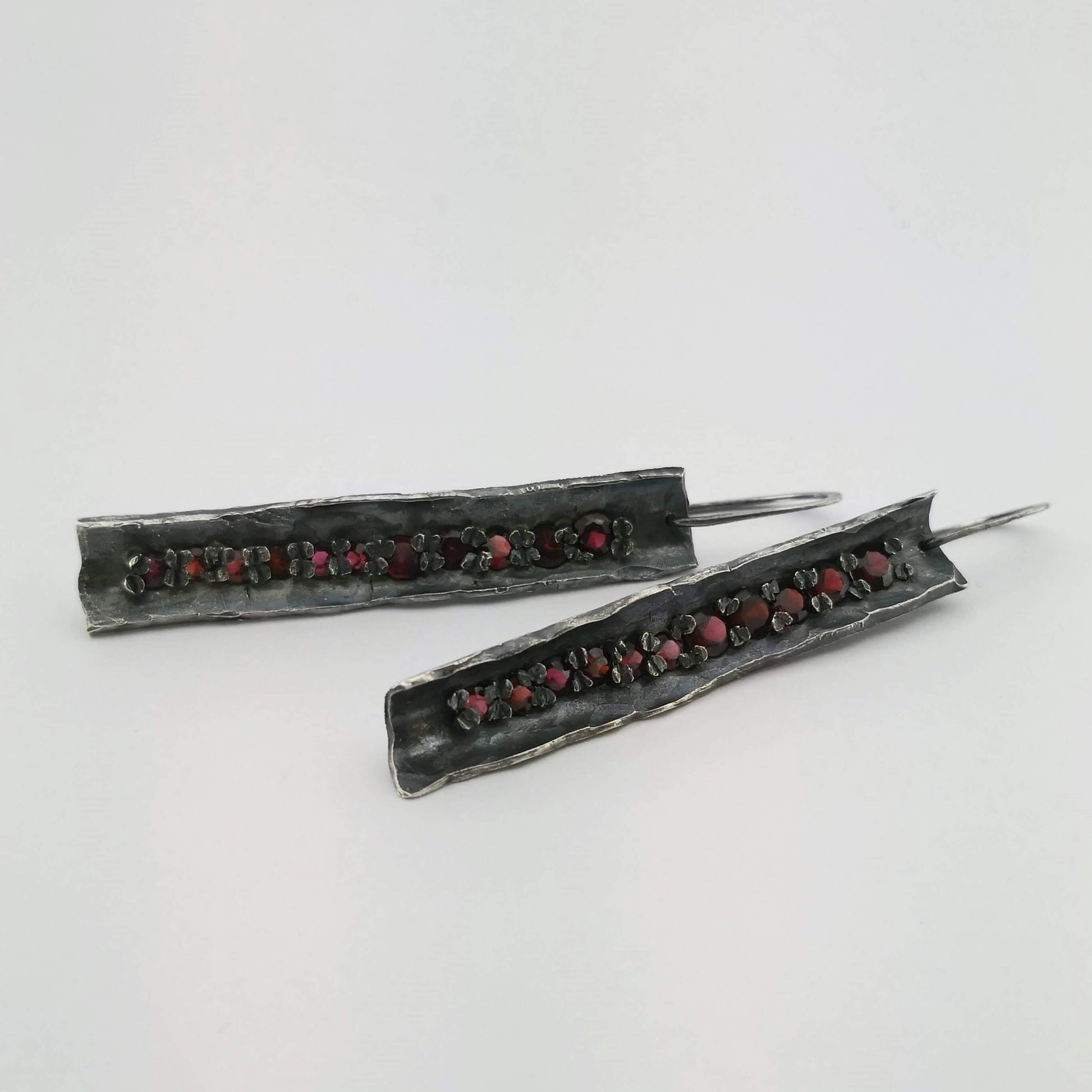 These unique earrings are hand crafted in oxidised sterling silver and set with graduated sizes of garnets. NZ jeweller Vaune Mason is known for her love of colourful gemstones and exciting setting style.