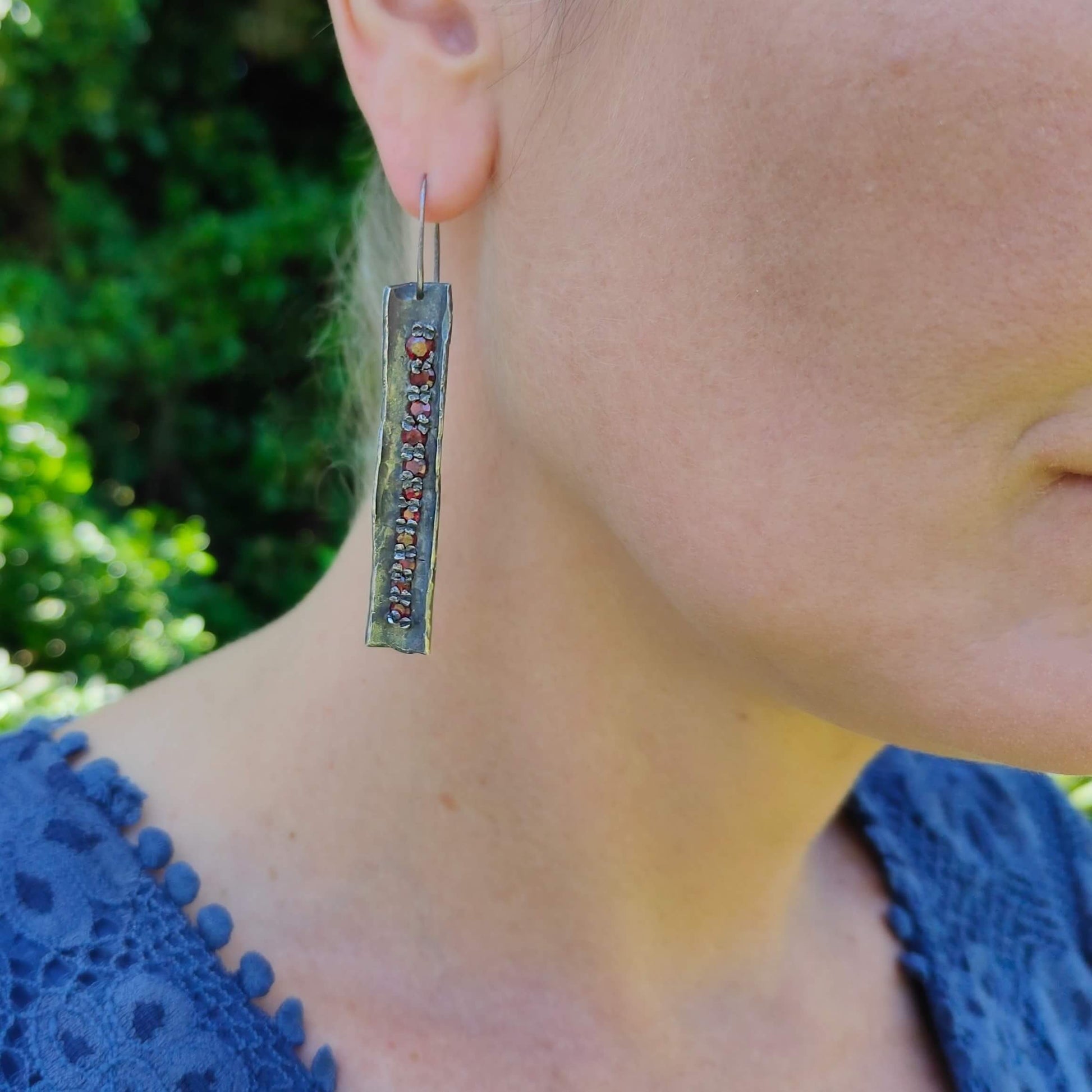 These unique earrings are hand crafted in oxidised sterling silver and set with graduated sizes of garnets. NZ jeweller Vaune Mason is known for her love of colourful gemstones and exciting setting style.