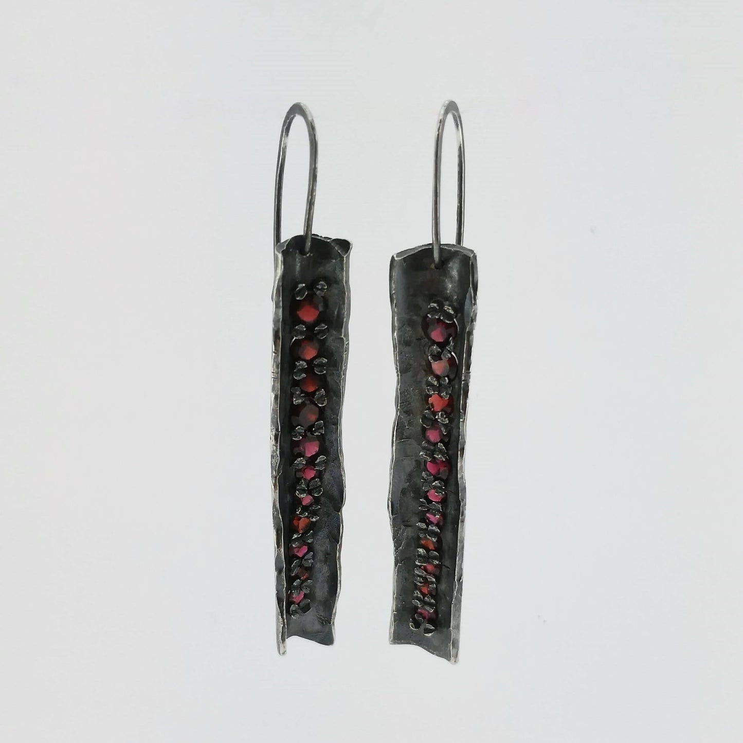 These unique earrings are hand crafted in oxidised sterling silver and set with graduated sizes of garnets. NZ jeweller Vaune Mason is known for her love of colourful gemstones and exciting setting style.