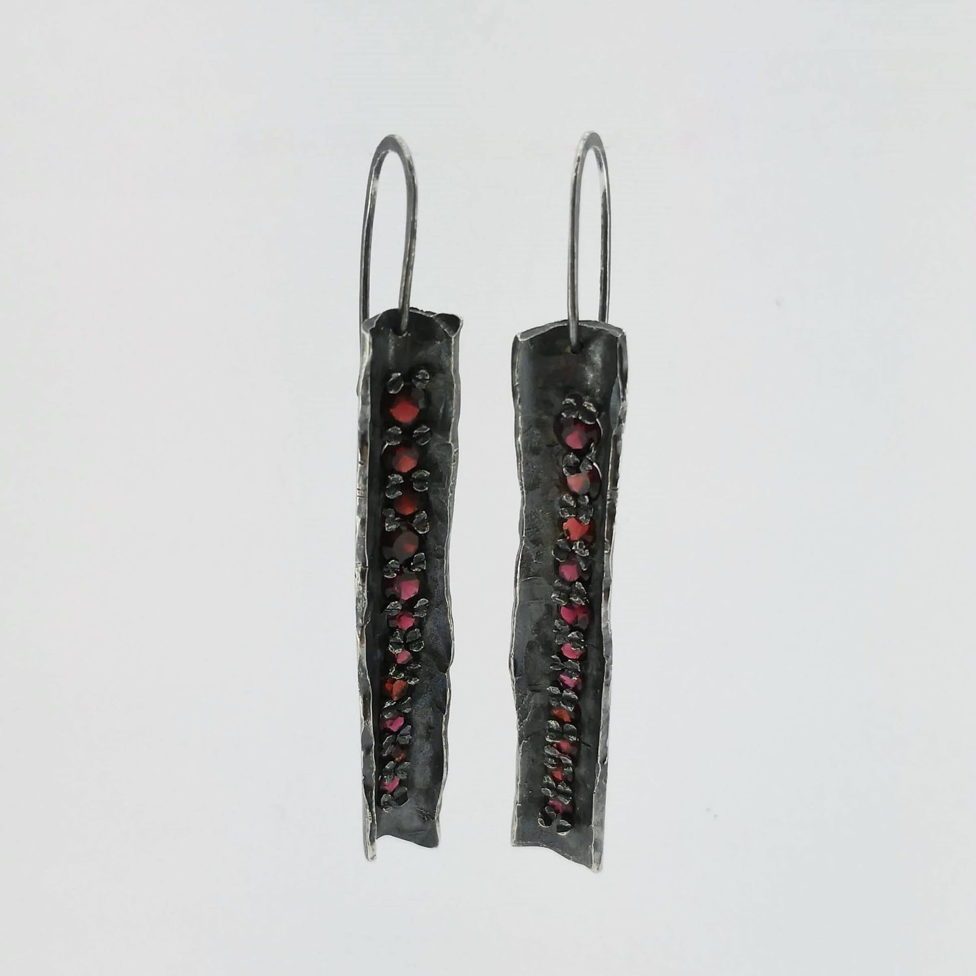 These unique earrings are hand crafted in oxidised sterling silver and set with graduated sizes of garnets. NZ jeweller Vaune Mason is known for her love of colourful gemstones and exciting setting style.