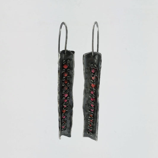 These unique earrings are hand crafted in oxidised sterling silver and set with graduated sizes of garnets. NZ jeweller Vaune Mason is known for her love of colourful gemstones and exciting setting style.