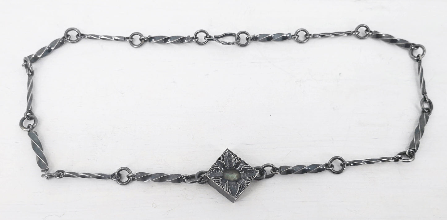 This statement necklace handcrafted by NZ jeweller Vaune Mason features hand-twisted silver chain links and a one-of-a-kind setting.