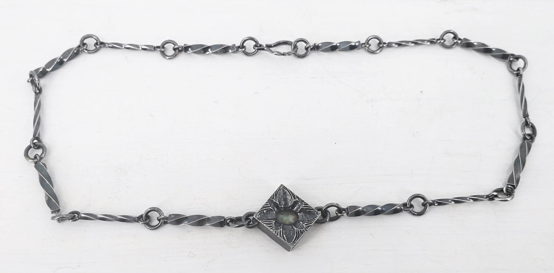This statement necklace handcrafted by NZ jeweller Vaune Mason features hand-twisted silver chain links and a one-of-a-kind setting.