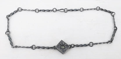 This statement necklace handcrafted by NZ jeweller Vaune Mason features hand-twisted silver chain links and a one-of-a-kind setting.