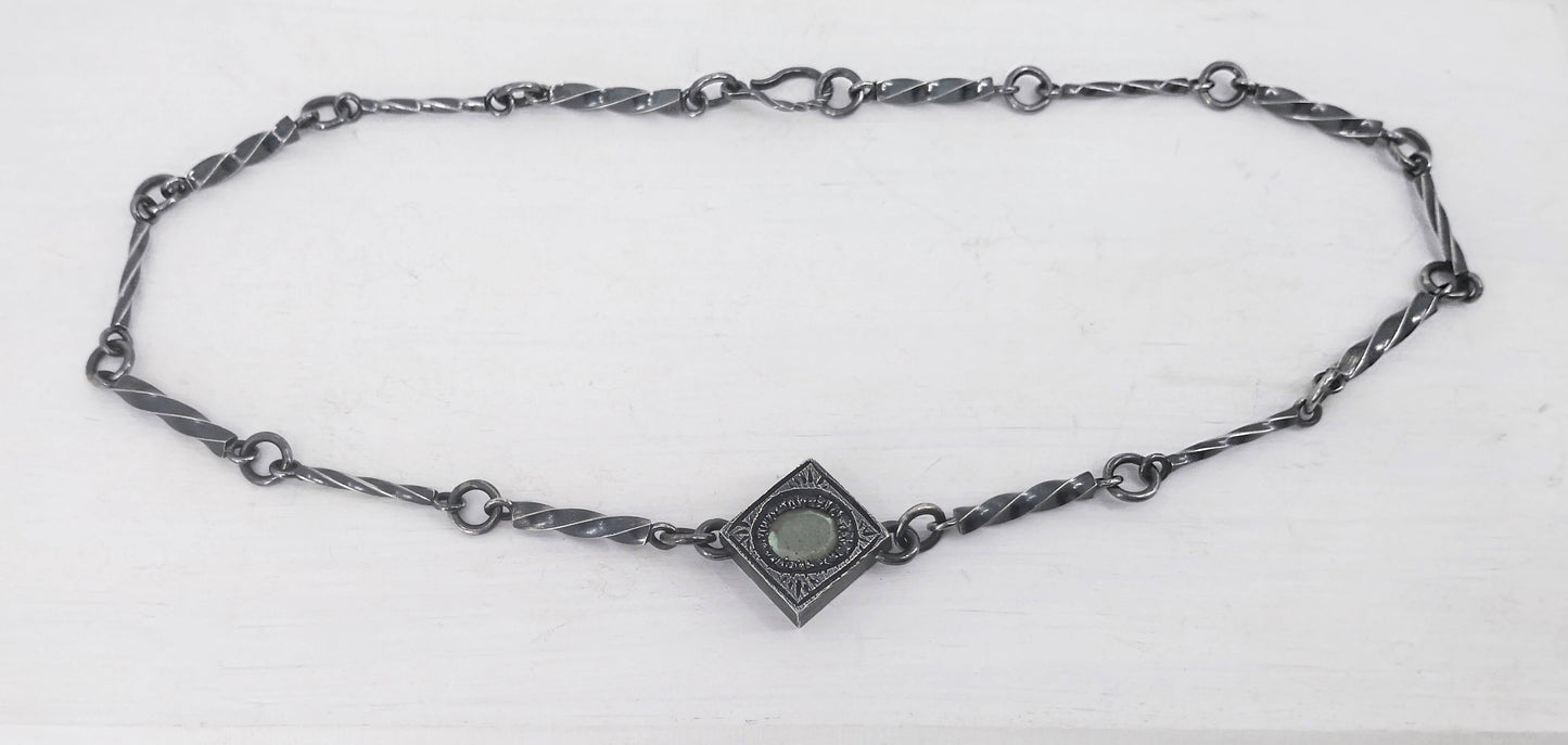 This statement necklace handcrafted by NZ jeweller Vaune Mason features hand-twisted silver chain links and a one-of-a-kind setting.