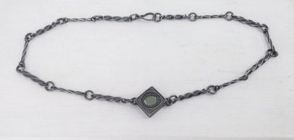 This statement necklace handcrafted by NZ jeweller Vaune Mason features hand-twisted silver chain links and a one-of-a-kind setting.