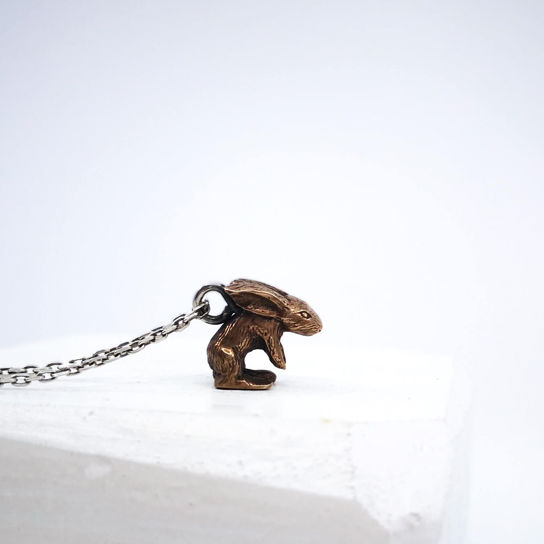 The Very Tiny Bunny necklace by Vaune Mason features a delicately carved bunny charm cast in warm bronze on a sterling silver chain.